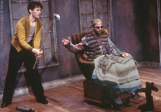 Clov (David Fitzgerald) hands Hamm (Matthew Lawler) the gaff, saying 'stick it up!'.